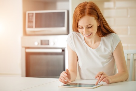 happy smiling woman sitting with digital tabletの写真素材