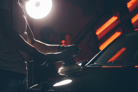 Car detailing - man with orbital polisher in auto repair shop. Selective focus.の写真素材