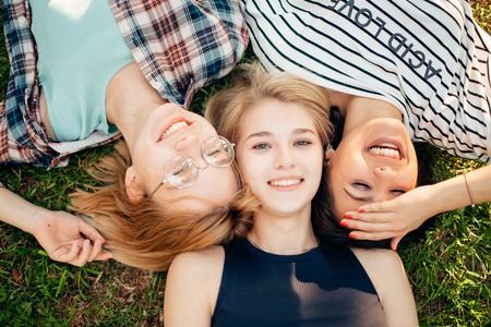 Having best time with friends. group of students lying on grass enjoyingの写真素材