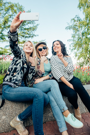 hipster friends do selfie photo portrait in the park while summer sunsetの写真素材