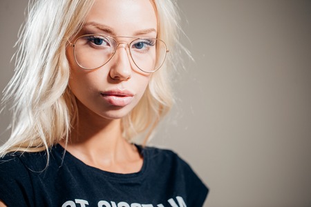 Young thoughtful secretary in glasses dreaming on gray backgroundの写真素材