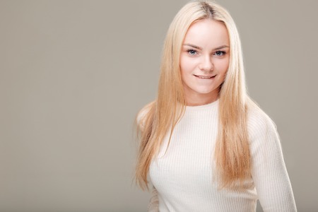 smiling flirting woman with long curly hair and finger on lipの写真素材