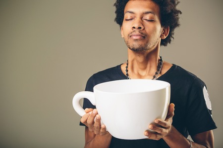 man holding funny huge and oversized cup of black coffeeの写真素材