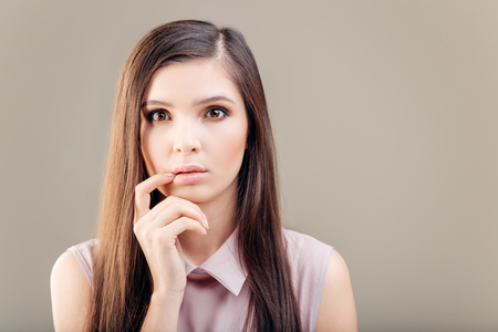 beautiful brunette woman with a finger at her mouth on white backgroundの写真素材