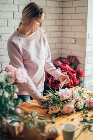 Florist at work: woman making fashion modern bouquet of different flowersの写真素材