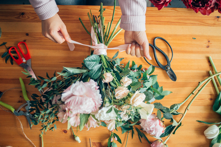 hands of florist against desktop with working tools and ribbons on wood tableの写真素材