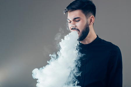 Vaper smoke electronic cigarette outdoor near wallの写真素材
