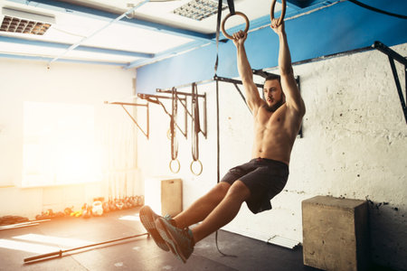 fit man pulling up on gymnastic rings.