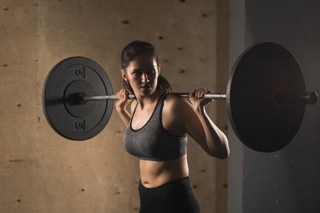 muscular woman in a gym doing heavy weight exercises with barbellの写真素材