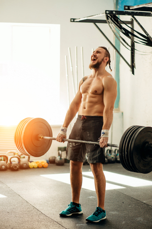 man lifting weights. muscular man workout in gym doing exercises with barbellの写真素材