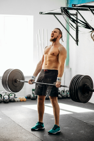 man lifting weights. muscular man workout in gym doing exercises with barbellの写真素材