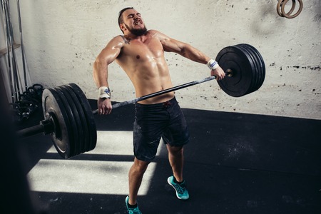 man lifting weights. muscular man workout in gym doing exercises with barbellの写真素材