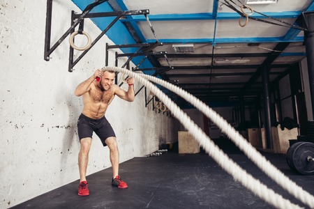 Men with battle rope battle ropes exercise in the fitness gymの写真素材