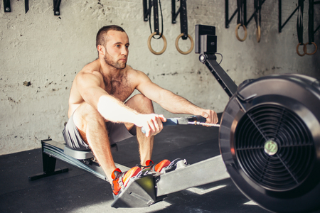 tired sporty male workouts on power exercise machine in a gym clubの写真素材