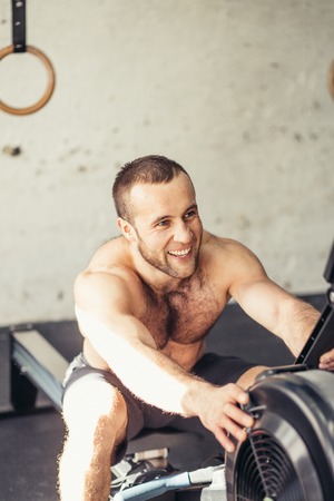 tired sporty male workouts on power exercise machine in a gym clubの写真素材