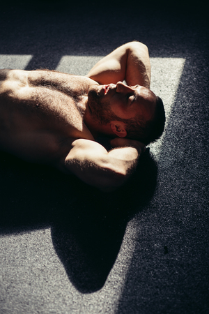 fitness male working out at the gym. Muscular young man doing stomach exercises.の写真素材