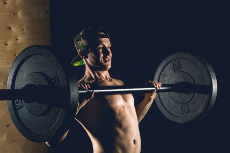 Sport, workout. Closeup portrait of a muscular man workout with barbell at gym.の写真素材
