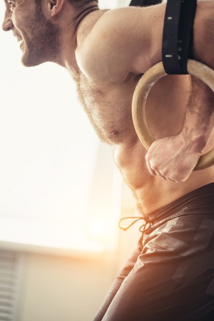 close up Fitness handsome man doing dipping exercise using rings in the gymの写真素材