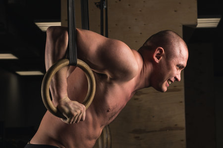 fit man pulling up on gymnastic rings.