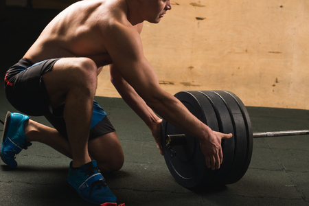 Handsome weightlifter preparing for training with barbellの写真素材
