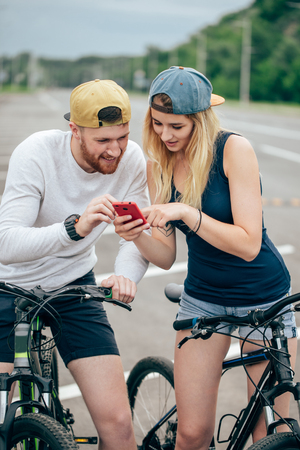 couple of tourists watch the phone during a bike rideの写真素材