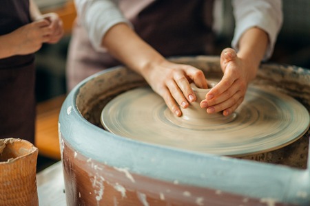 Hands of young potter, close up hands made cup on pottery wheelの写真素材