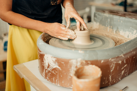 Female potter working at throwing wheel at studio. Clay workshopの写真素材