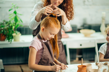 redhead Mother and kid daughter at home molded from clay and play togetherの写真素材
