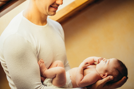 Father holding newborn baby near windowの写真素材