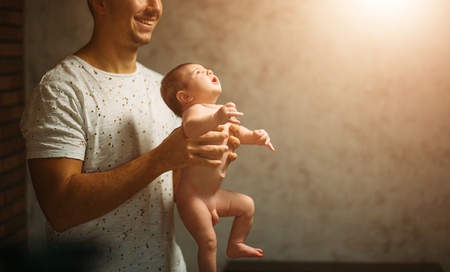 Father lying with cute baby daughter on bedの写真素材