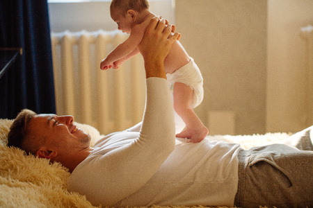 father playing with adorable baby in bedroomの写真素材