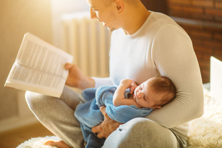 Young father and reading book to little baby