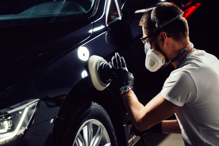 Car detailing - man with orbital polisher in auto repair shop. Selective focus.の写真素材