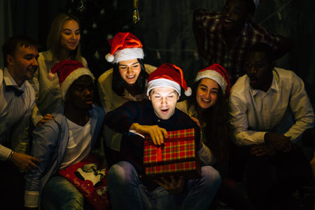 happy smiling friends opening magic Christmas gift