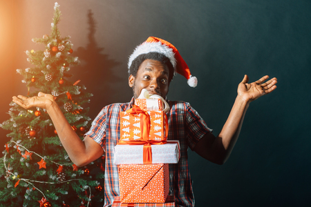 Afro american guy with charming smile holding Christmas gift in handsの写真素材
