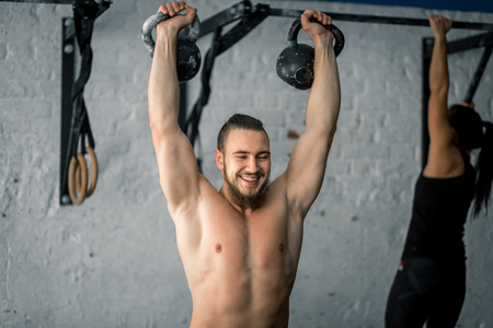 man lifting two kettlebell workout exercise at gymの写真素材