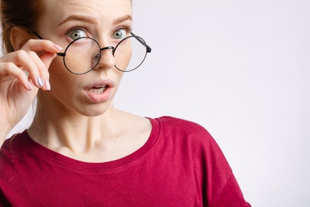 beautiful redhair girl wearing glasses shocking with somethingの写真素材
