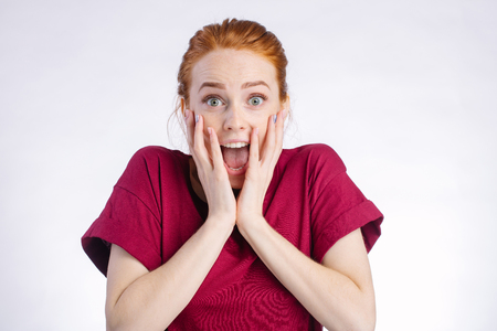 Surprised redhead woman wide open mouth and touching her head. white backgroundの写真素材