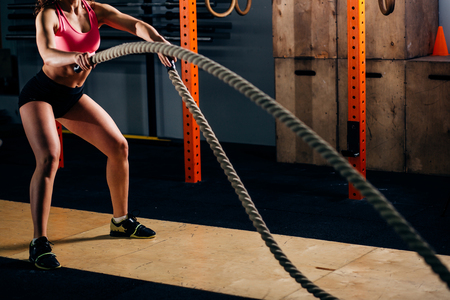 Athletic young woman doing some cross fit exercises with rope outdoorの写真素材
