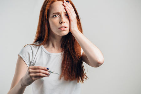 Headache. Sick Woman with Thermometer looking at camera. Flu. Woman Caught Coldの写真素材