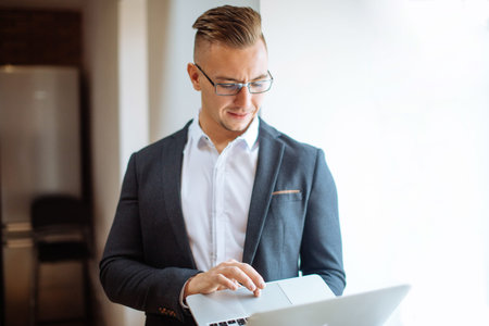 handsome man wearing glasses working with laptop in office