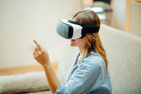 woman adjusting her VR headset and smiling while sitting on the carpet at homeの写真素材