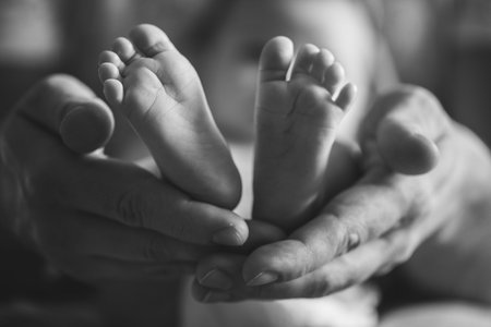 Parent holding in hands feet of newborn baby
