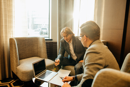 Two male employees consulting with laptop in cafeの写真素材