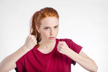 angry woman standing with raised knuckles on white backgroundの写真素材