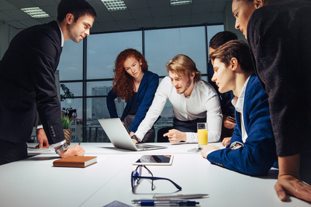 Smiling Female And Handsome Male Co-Workers Sitting At Table, Looking At Laptopの写真素材