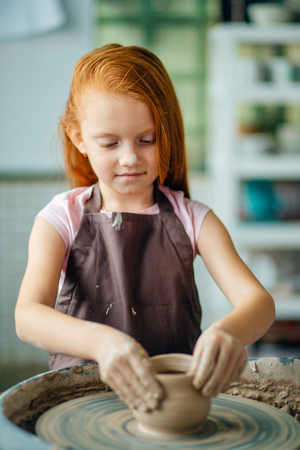 redhead Child sculpts from clay pot. workshop on modeling on potters wheel.の写真素材
