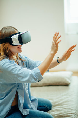 young woman wearing VR headset and smiling while sitting on couch at home