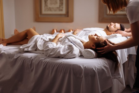 Young couple receiving head massage at beauty spaの写真素材