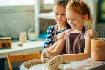 working process with clay potter wheel. Two girls making pottery in studioの写真素材